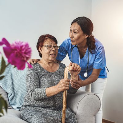 Caregiver, carer hand holding elder hand woman in hospice care. Philanthropy kindness to disabled concept.Public Service Recognition Week. Attentive young doctor talks with female patient